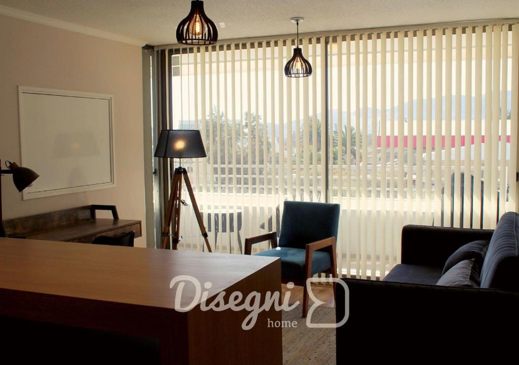 a living room with chairs and a table and a large window at Departamento Av. Los Carrera Copiapó Disegni 07 in Copiapó