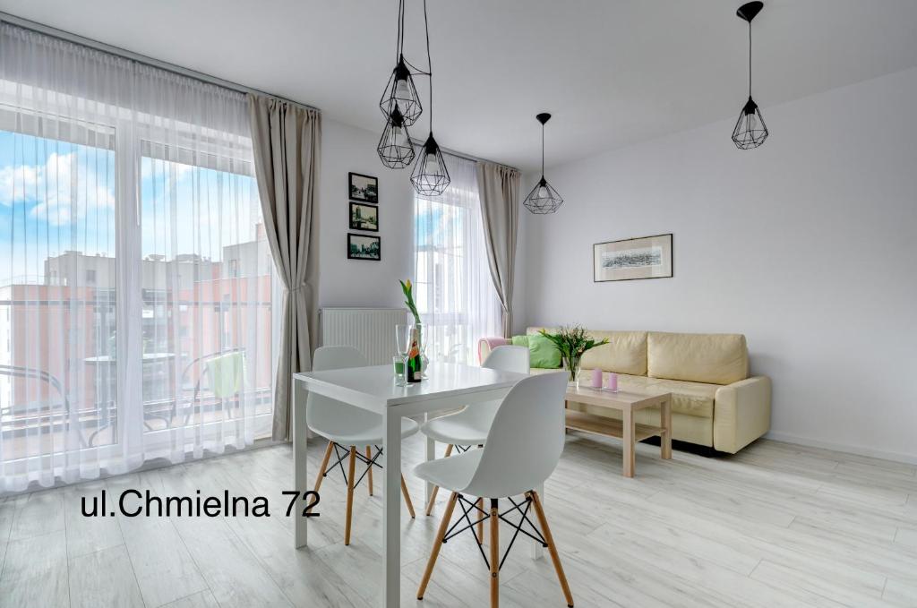 - un salon avec une table et des chaises blanches dans l'établissement Twój Salon-Apartamenty Stare Miasto, à Gdańsk
