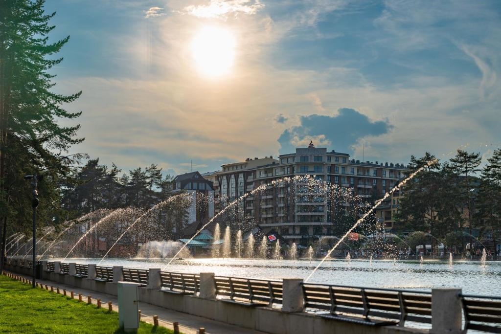 a fountain in a lake with a building in the background at 5 STARS - Luxury Premium WELLNESS RESORT Zlatibor in Zlatibor