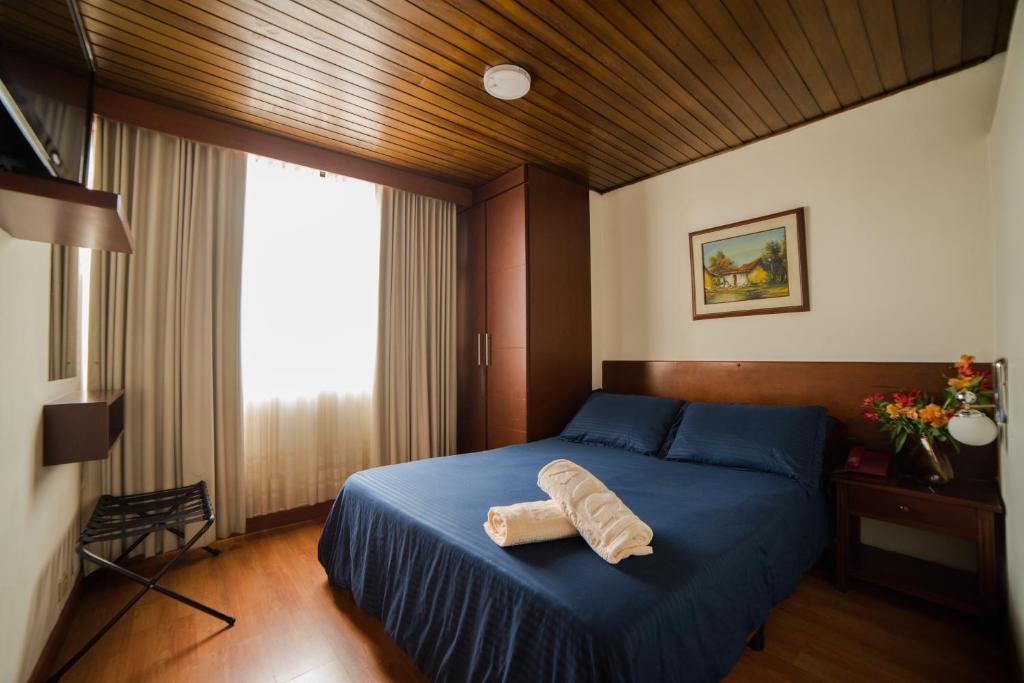 - une chambre avec un lit bleu et une serviette dans l'établissement Apartamentos Galerías, à Bogotá