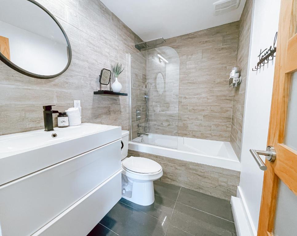 a bathroom with a toilet and a tub and a mirror at Complexe LIVTremblant by Gestion ELITE - LIV6 in Mont-Tremblant