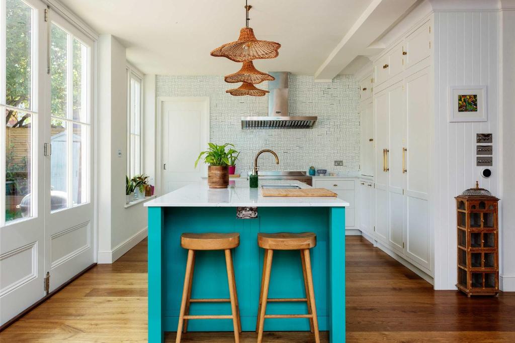 una cocina con una isla azul con 2 taburetes en Veeve - Cyan Gardens en Londres