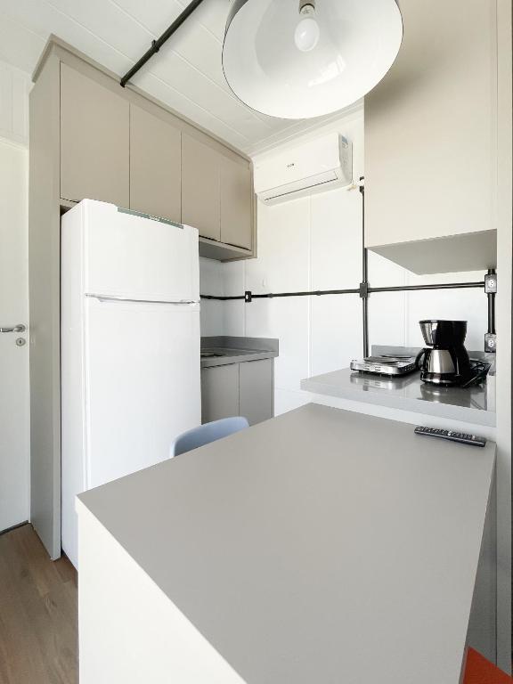 uma cozinha branca com um frigorífico branco e uma mesa em Casa Container Completa! - Beija Flor em Siderópolis