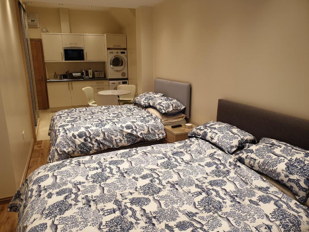 London Luxury Apartments 5 min walk from Ilford Station, with FREE PARKING & FREE WIFI في إلفورد: سريرين في غرفة صغيرة مع مطبخ