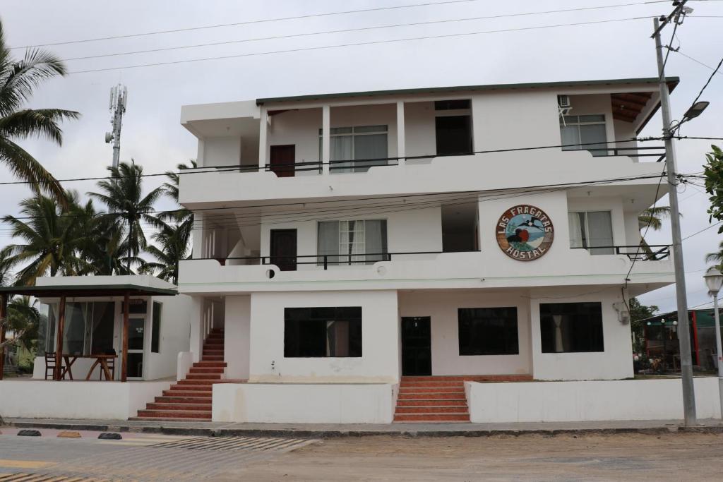 a large white building with stairs in front of it at Hostal Las Fragatas in Puerto Villamil