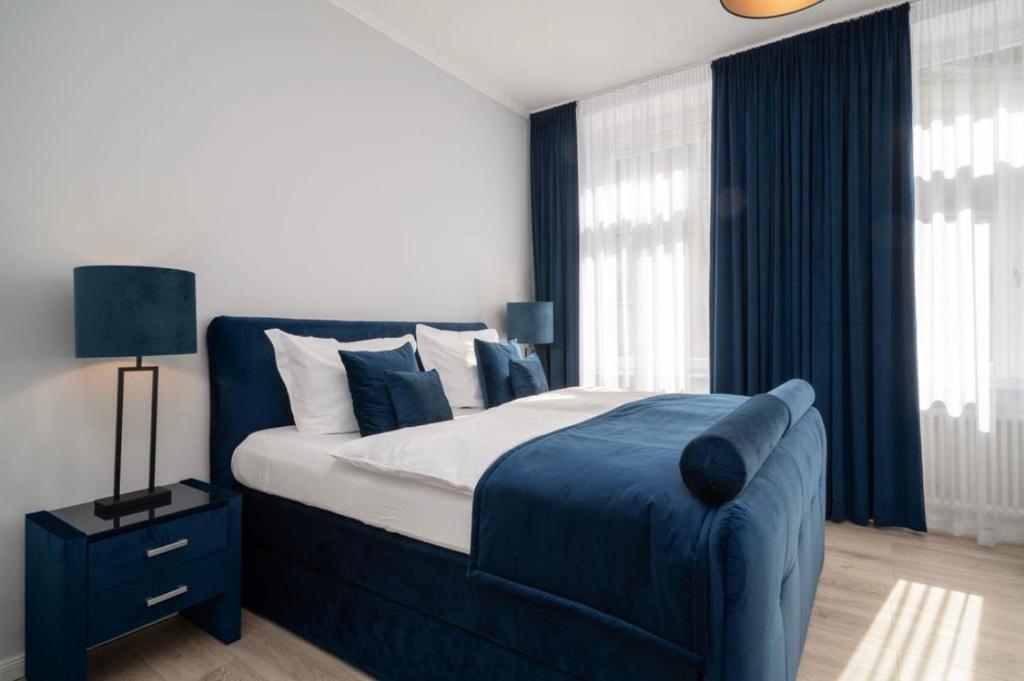 a bedroom with a blue and white bed and windows at Blue Sky Apart Center Baden-Baden in Baden-Baden