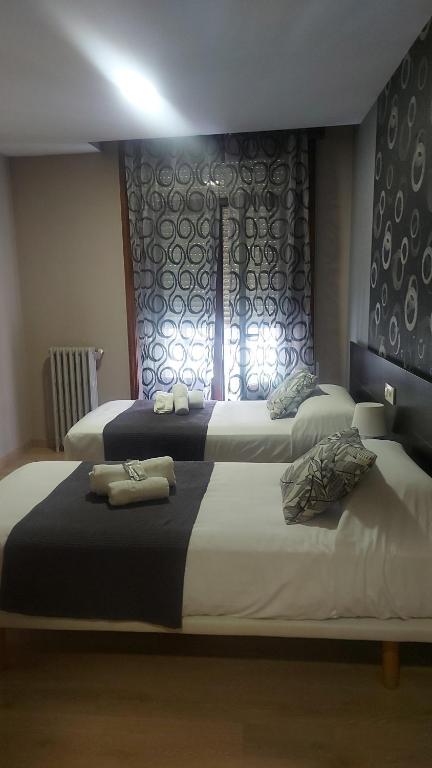 two beds in a hotel room with a window at New J&J Hostel in Ourense