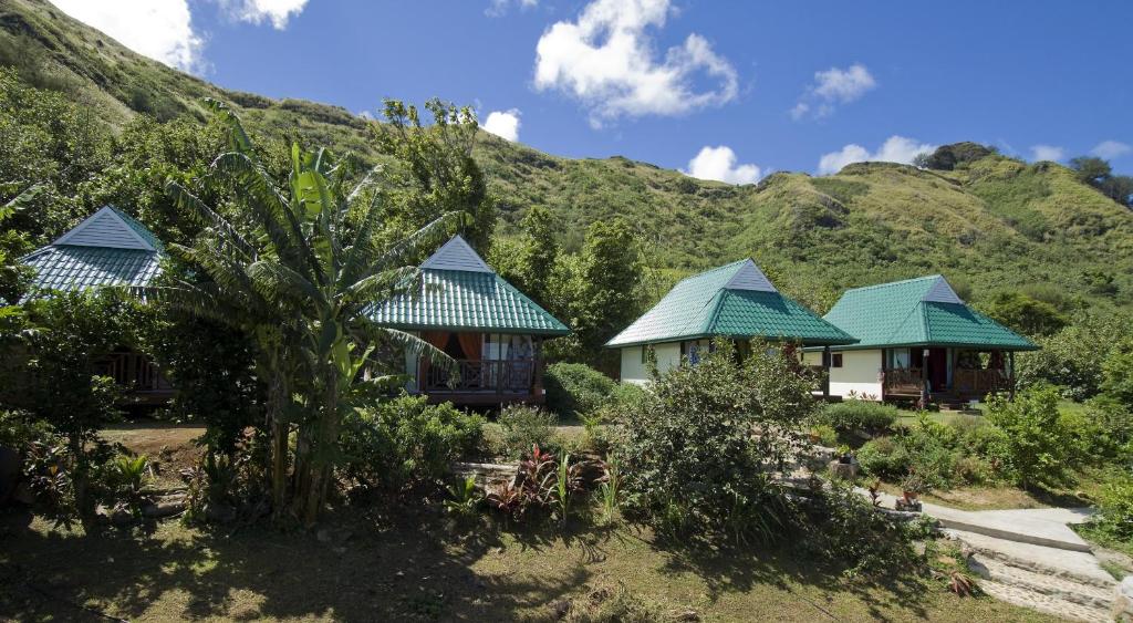 un groupe de maisons avec des montagnes en arrière-plan dans l'établissement Pension Vaimano-Raivavae, à Vaiuru