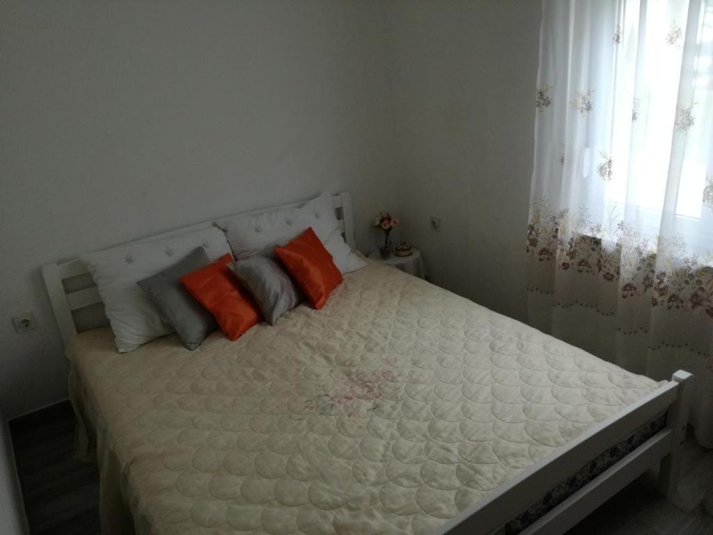 ein weißes Bett mit orangefarbenen und grauen Kissen darauf in der Unterkunft Apartments by the sea Ladjin Porat, Paklenica - 17624 in Starigrad-Paklenica