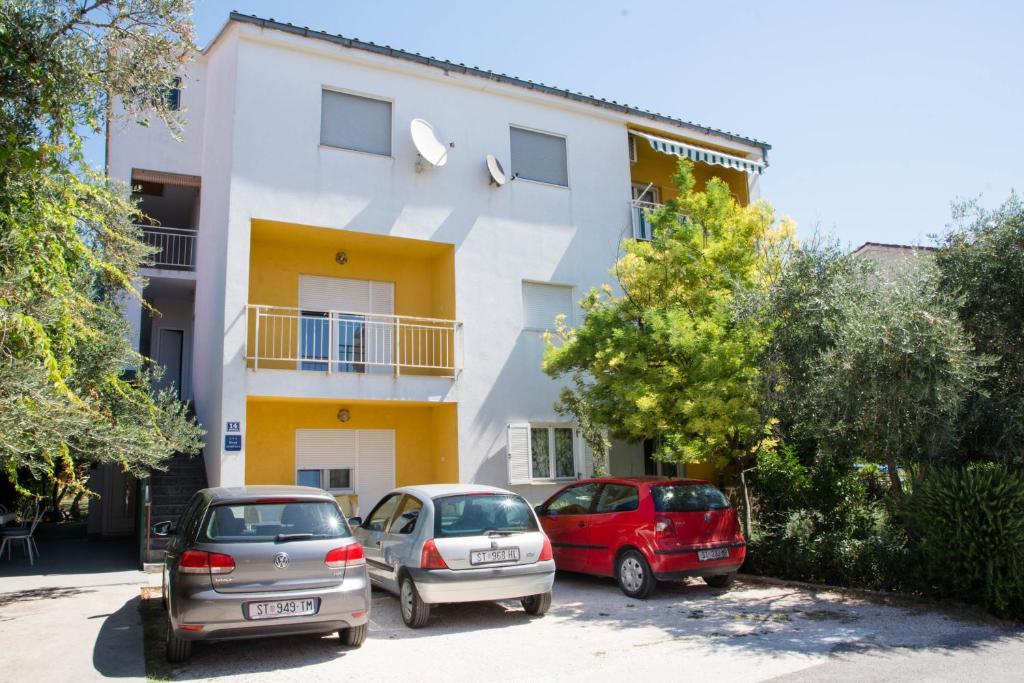 3 auto parcheggiate di fronte a un edificio di Apartments with a parking space Kastel Luksic, Kastela - 17691 a Kaštela (Castelli)