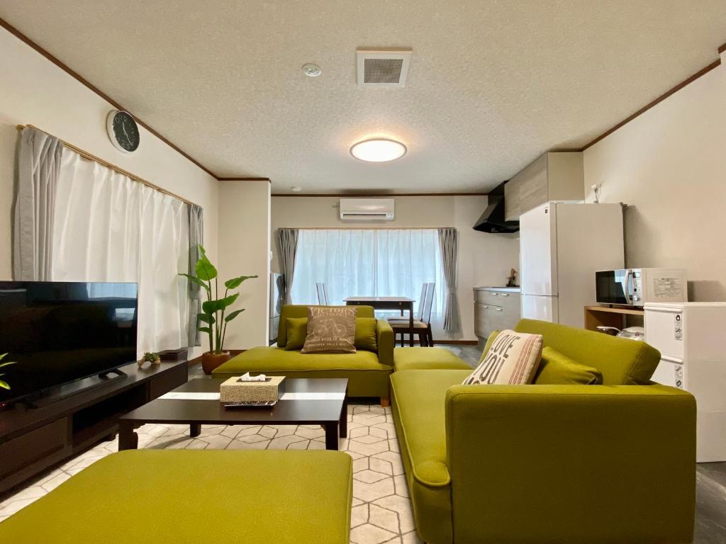 a living room with two green chairs and a television at ワンハウス新小岩 in Tokyo