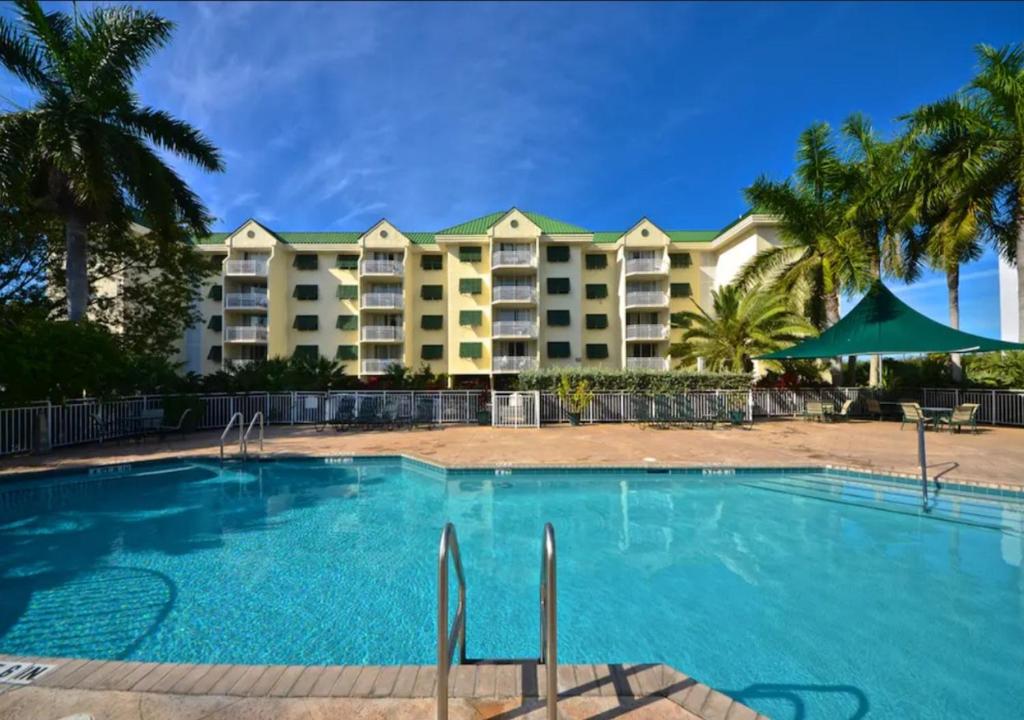 una piscina frente a un complejo con palmeras en Sunrise Suites by TO, en Key West