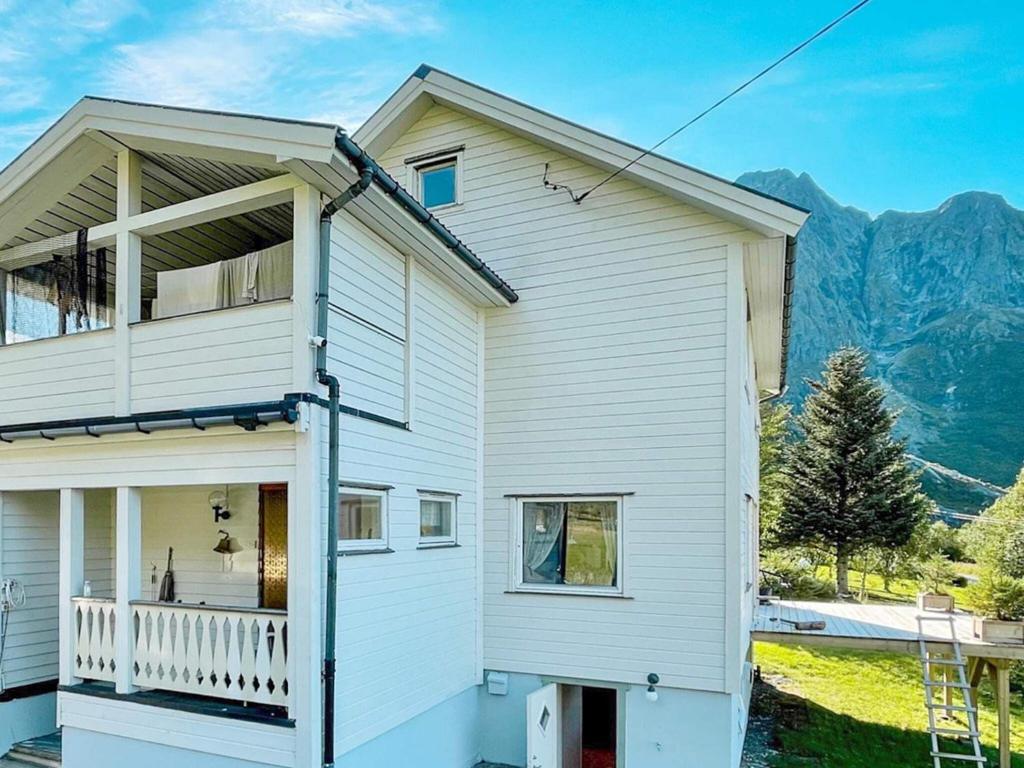 a white house with a balcony and mountains in the background at Two-Bedroom Holiday home in Laupstad 4 in Vestpollen