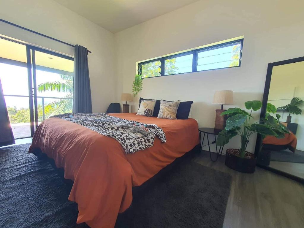 een slaapkamer met een bed met een oranje deken bij Tematas Mountain Villa in Avarua