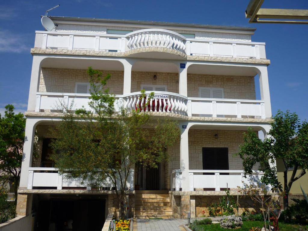 ein weißes Gebäude mit Balkon darüber in der Unterkunft Apartments with a parking space Vrsi - Mulo, Zadar - 17753 in Vrsi