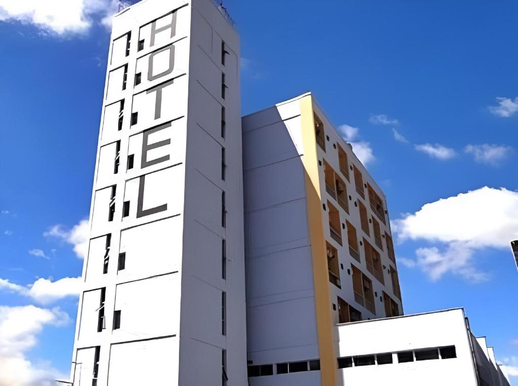 a tall white building next to two other buildings at Olympia Hotel in Lorena