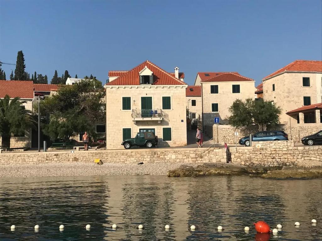 a group of buildings next to a body of water at Apartments by the sea Sutivan, Brac - 17796 in Sutivan