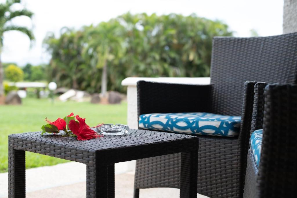 a black wicker chair with a table with flowers on it at Fiji Gateway Hotel in Nadi