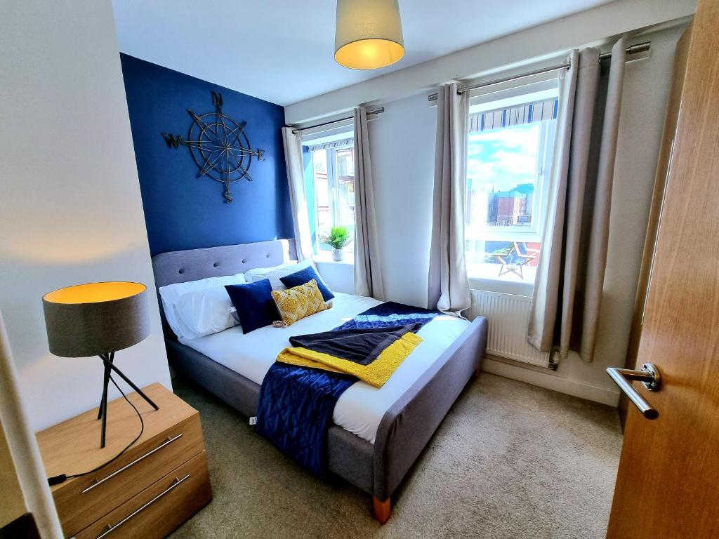 een slaapkamer met een bed met blauwe muren en ramen bij Luxury 2-Bedroom Service Apartment with Balcony in Manchester