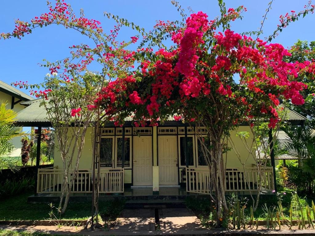 una casa con flores rosas en el porche en Lembah Rinjani Villa & Resto by ecommerceloka, en Sembalun Lawang