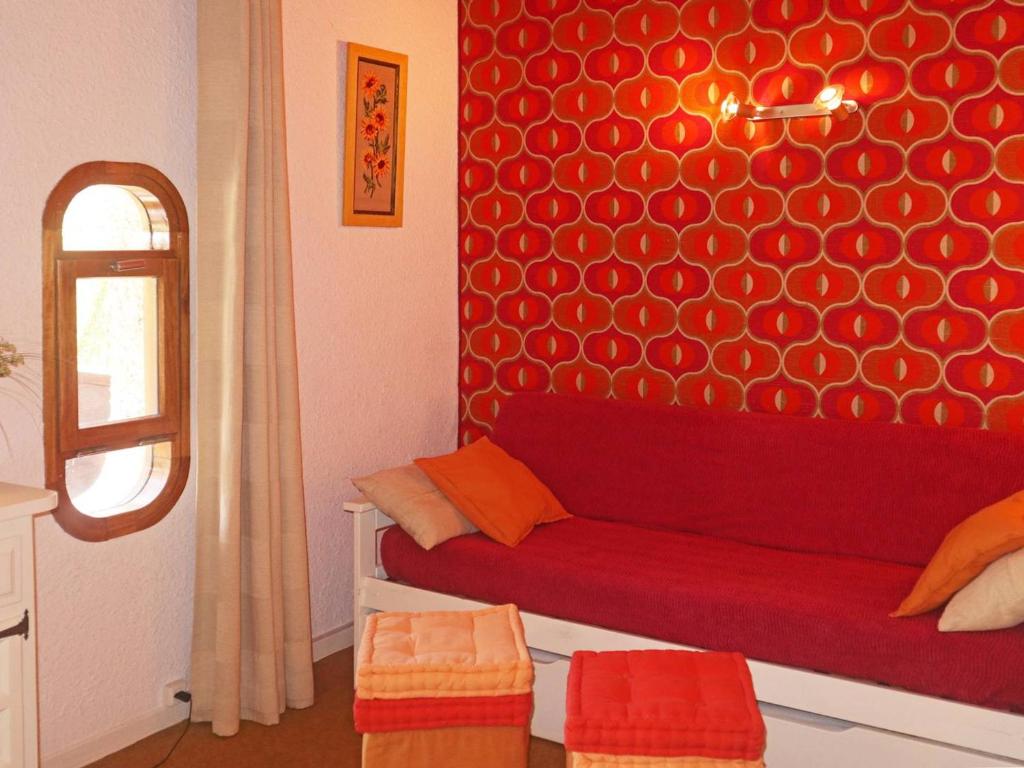 - un canapé rouge dans une chambre dotée d'un mur rouge dans l'établissement Studio pour 4 pers, skis aux pieds, garderie proche - FR-1-322-486, aux Orres