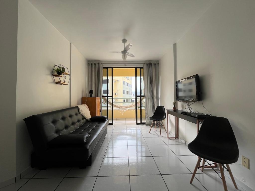 ein Wohnzimmer mit einem schwarzen Sofa und einem TV in der Unterkunft Precioso apartamento frente al mar in Florianópolis