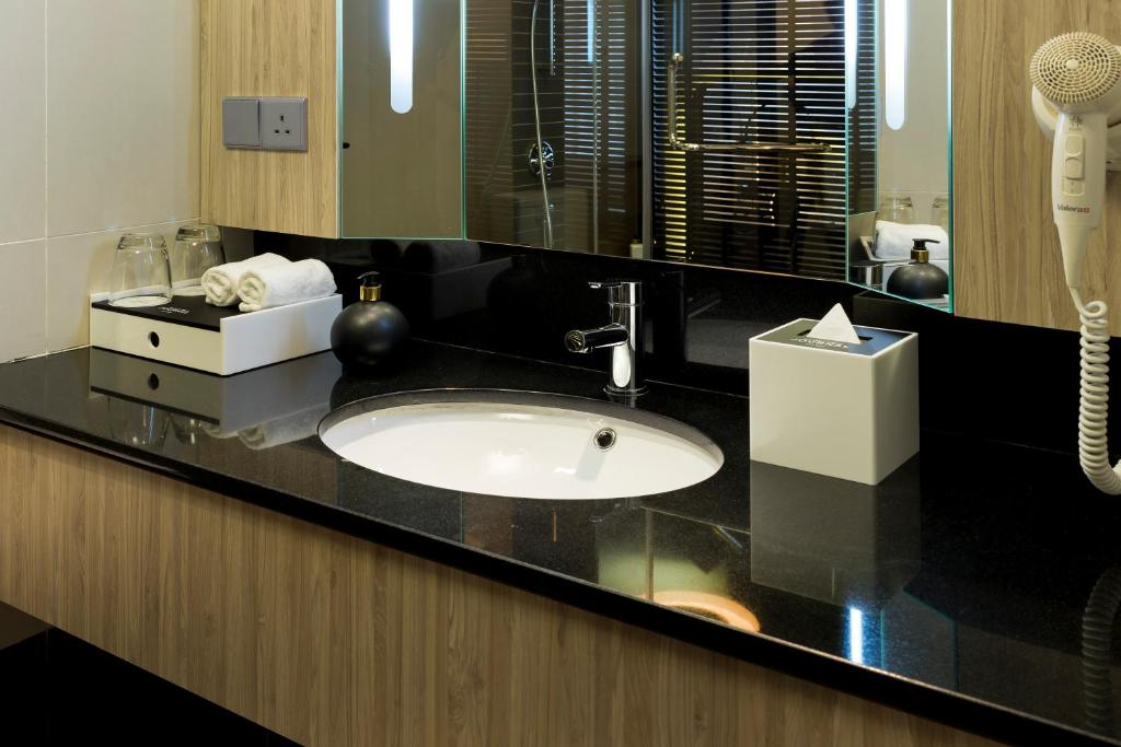 a bathroom counter with a sink and a mirror at The Kuala Lumpur Journal Hotel in Kuala Lumpur