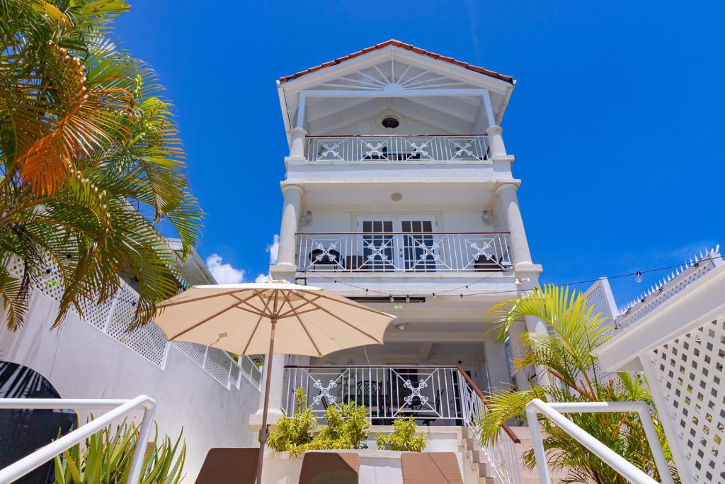 - un bâtiment blanc avec un parasol devant dans l'établissement Bianca Bay 3 Bedroom West Coast Beach Front Villa, à Saint James