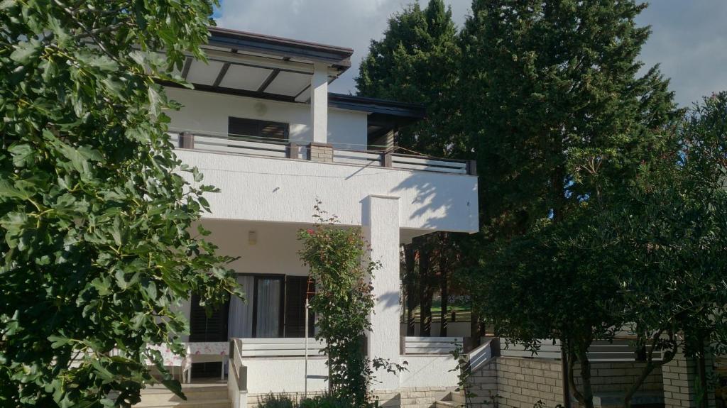 une maison blanche avec un balcon et des arbres dans l'établissement Apartments by the sea Novalja, Pag - 17859, à Novalja