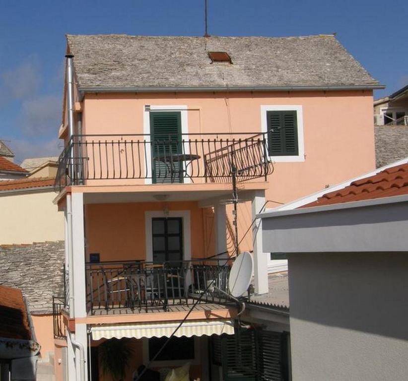 un bâtiment rose avec un balcon latéral dans l'établissement Apartments by the sea Primosten - 17975, à Primošten