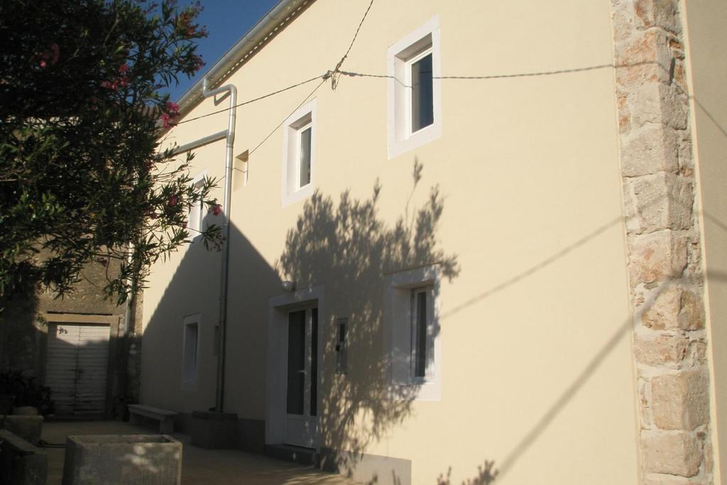 a white house with a shadow on the side of it at Holiday house with a parking space Olib - 17985 in Olib