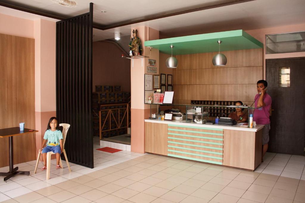 Maasin的住宿－馬阿辛GV酒店，一个女人和一个小女孩坐在厨房的椅子上