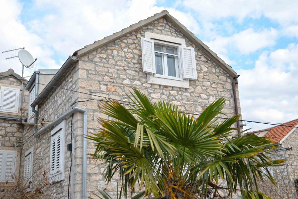 a stone house with a palm tree in front of it at Holiday house with WiFi Zlarin - 17998 in Zlarin
