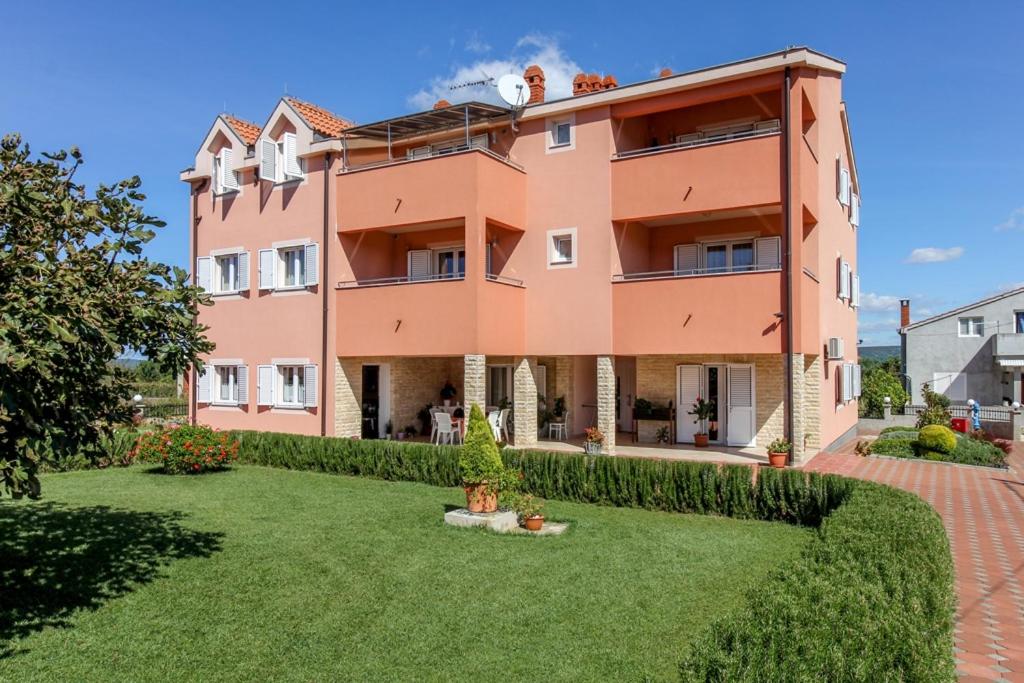 um grande edifício cor-de-rosa com um pátio verde em Family friendly apartments with a swimming pool Nevidjane, Pasman - 18054 em Neviđane