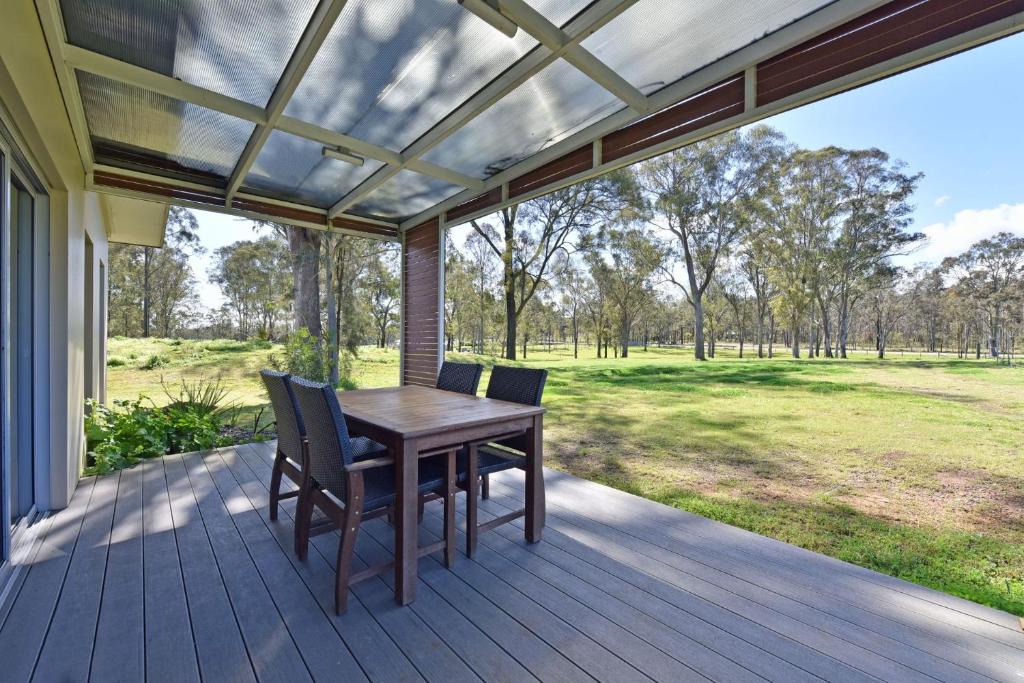 a porch with a wooden table and chairs on it at Ironbark Hill Villa 6 Cabernet Franc in Pokolbin