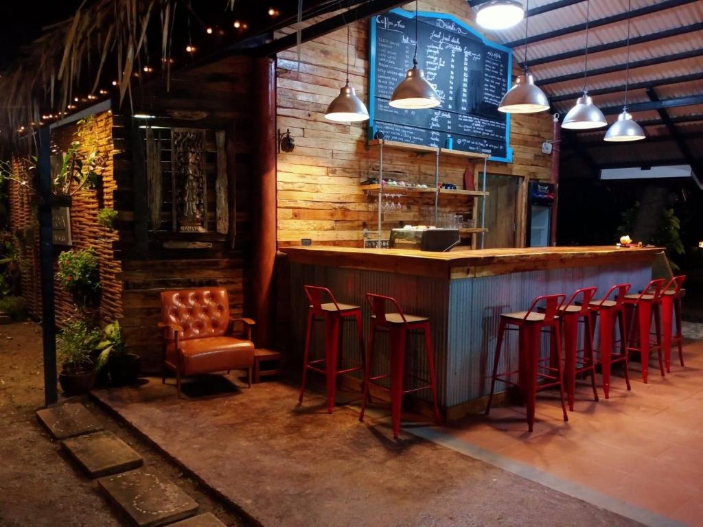 um bar com bancos vermelhos em frente a um restaurante em Cozy Garden Resort em Praia de Aonang