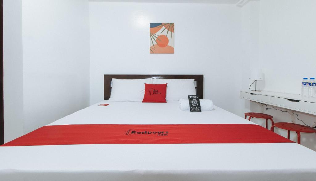 ein Hotelzimmer mit einem roten und weißen Bett mit zwei roten Stühlen in der Unterkunft RedDoorz near UST Sampaloc Manila in Manila