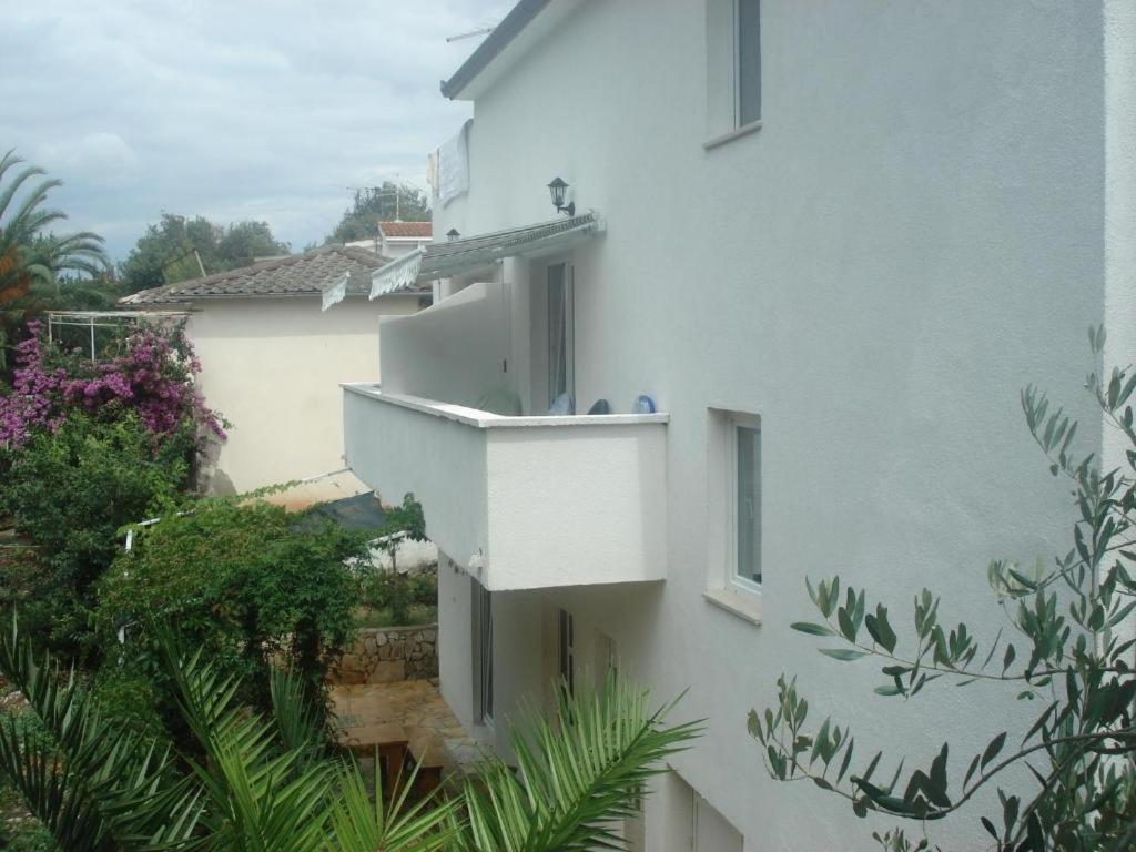 ein weißes Gebäude mit einem Balkon und Pflanzen in der Unterkunft Apartments by the sea Razanj, Rogoznica - 18089 in Rogoznica