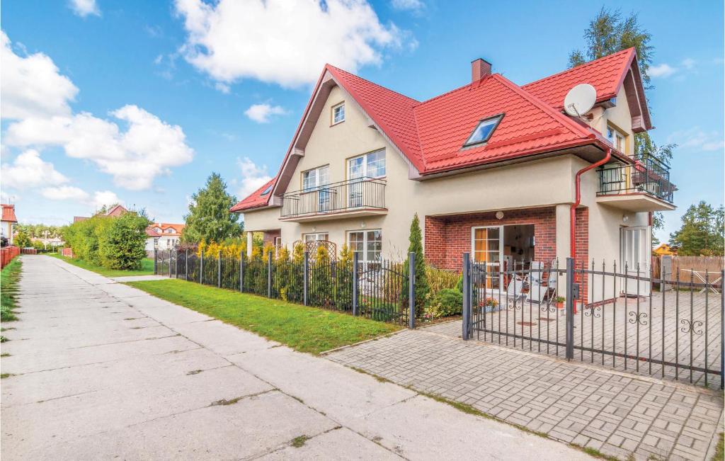 a house with a red roof and a fence at Cozy Apartment In Rowy With Kitchen in Rowy