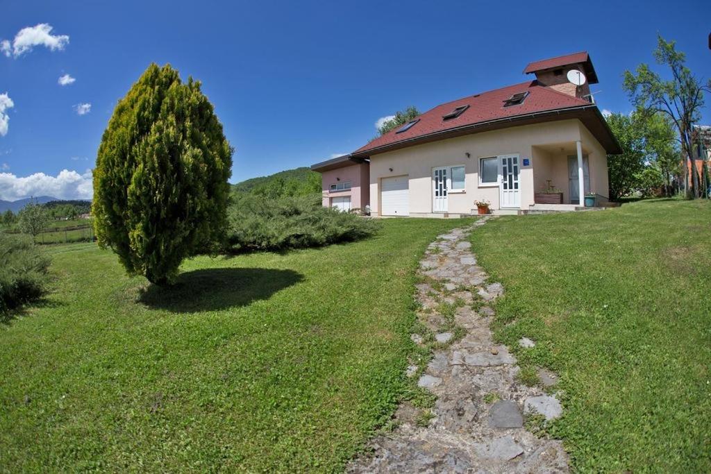 una casa en una colina con un árbol en primer plano en Apartments for families with children Otocac, Velebit - 18109, en Otočac