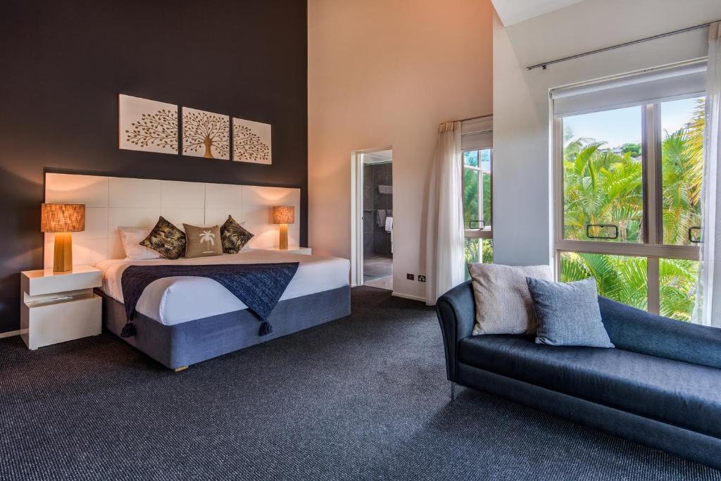un dormitorio con una cama y un sofá en Cooinda Gardens 6 on Hamilton Island by HamoRent, en Hamilton Island