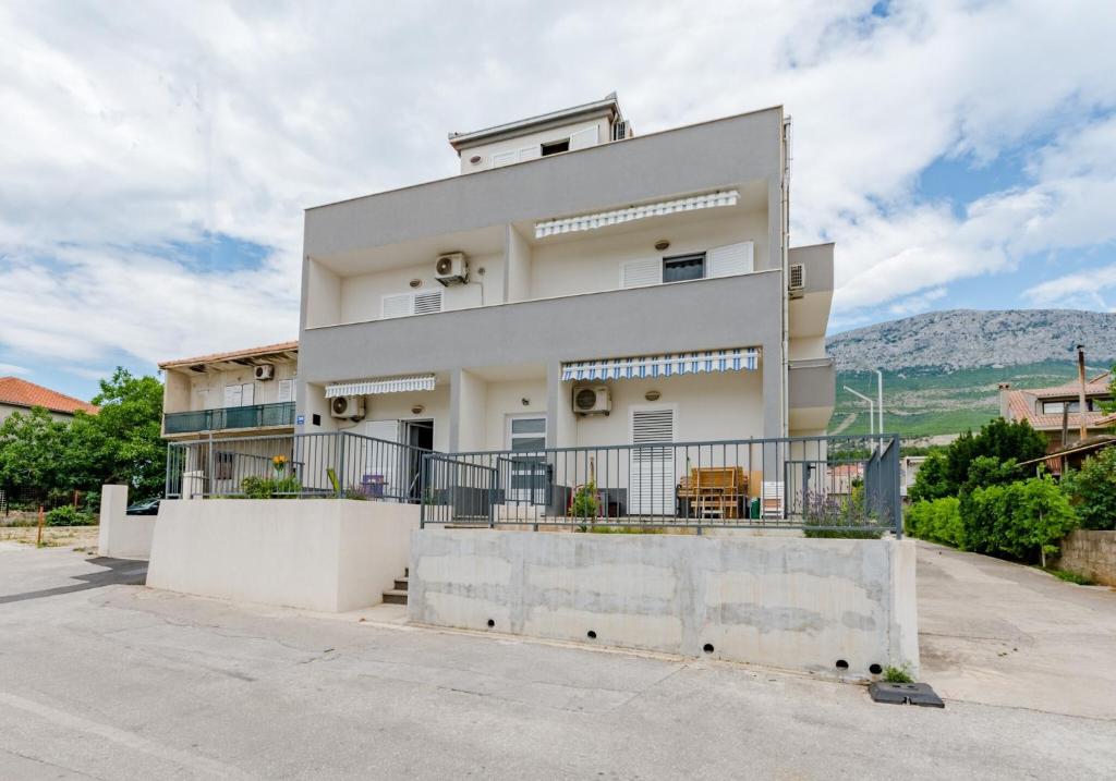 a white building with a fence in front of it at Apartments with a parking space Solin, Split - 18064 in Solin