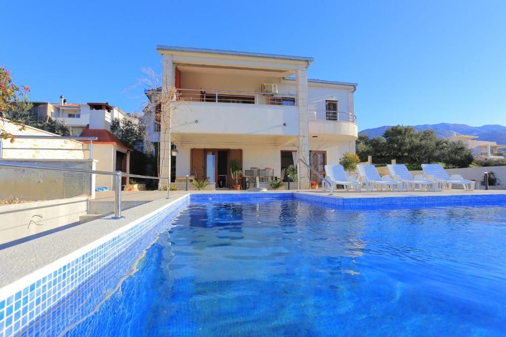 a villa with a swimming pool in front of a house at Apartments with a swimming pool Zrnovnica, Split - 18147 in Žrnovnica
