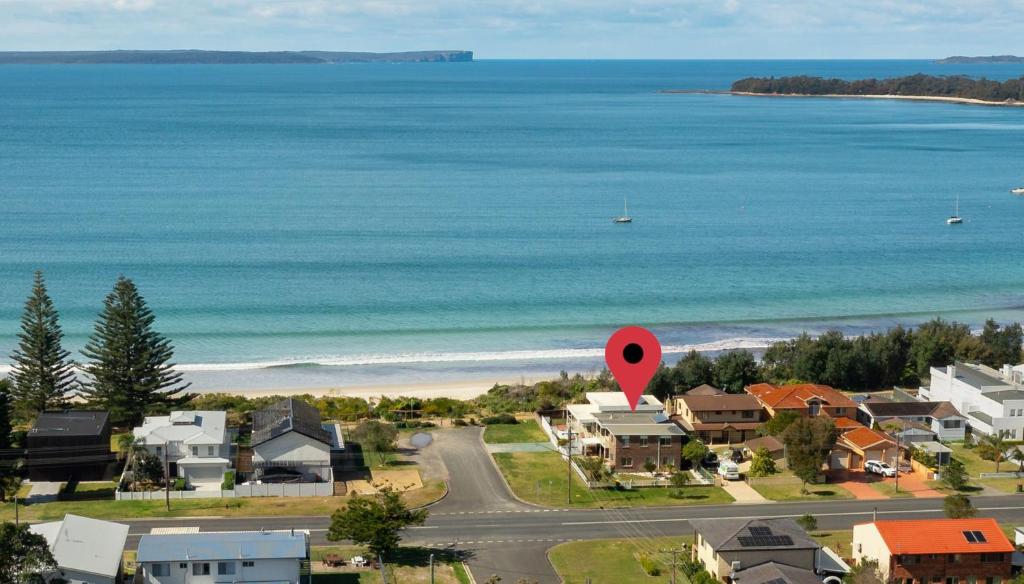 an aerial view of a beach with houses and a red marker at Poseidons Hideaway by Experience Jervis Bay in Vincentia