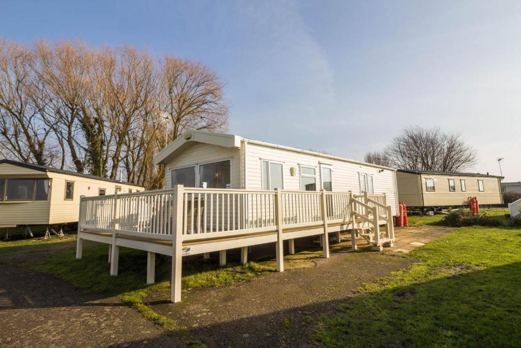 East MerseaにあるCaravan With Decking At Coopers Beach Holiday Park Ref 49012cwの隣接するモバイルホームを数軒用意しています。