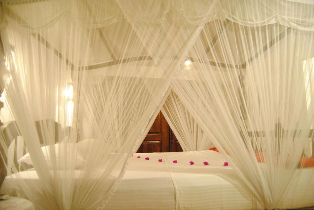 a bed with white mosquito netting on it at La Veranda Di Serena in Unawatuna