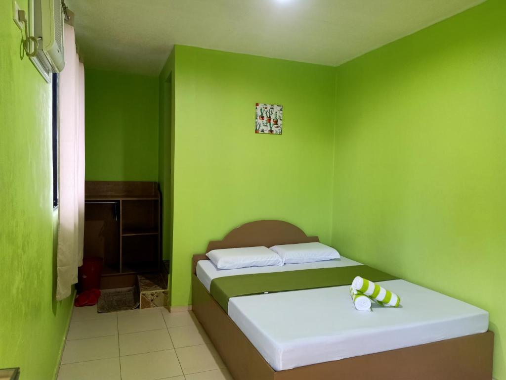 a bedroom with green walls and a bed in a room at Alona Guest House in Panglao