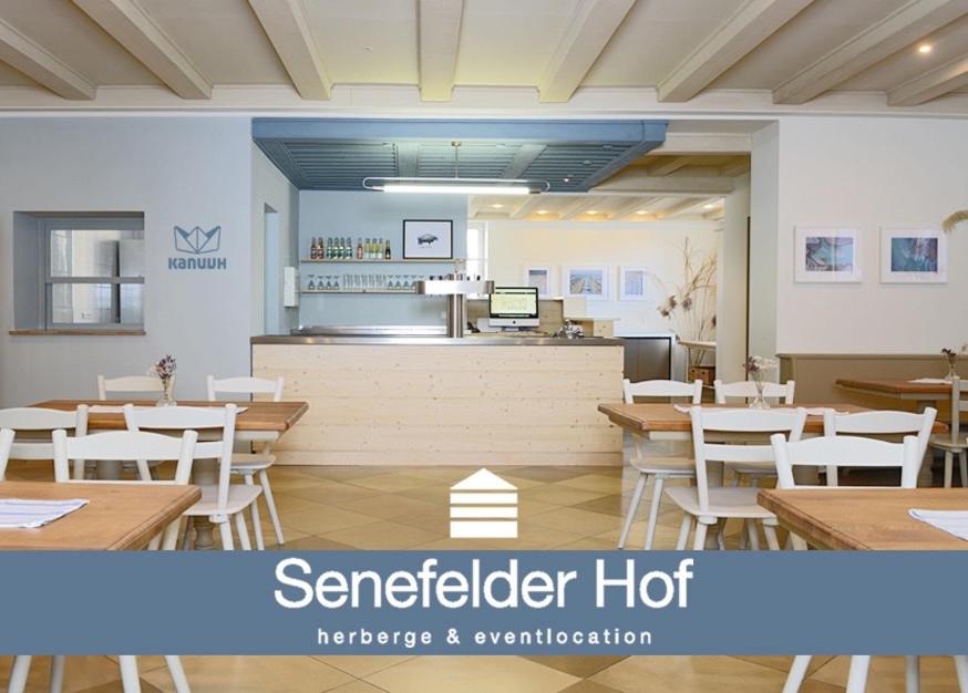 SolnhofenにあるSenefelder Hofの木製テーブルと白い椅子が備わるレストラン