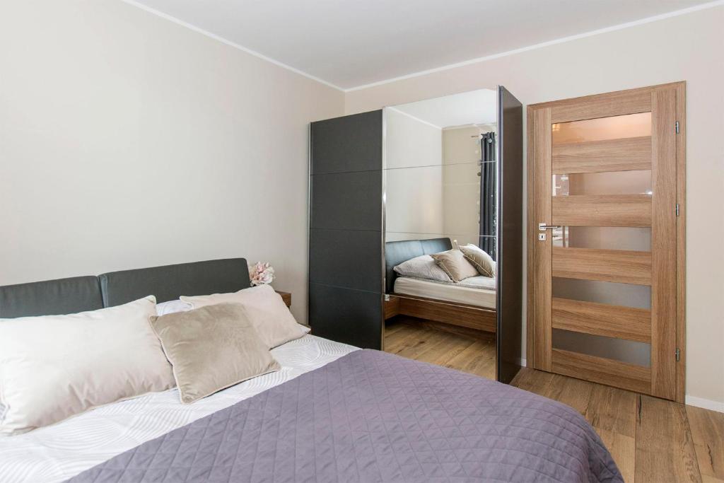 sypialnia z dużym łóżkiem i lustrem w obiekcie Carmel Rentyear Apartments w Gdańsku