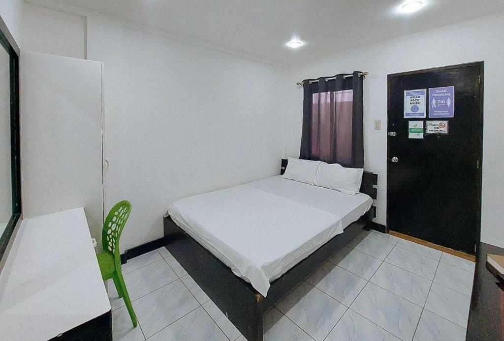 a small bedroom with a bed and a door at RedDoorz Buena's Pension in Puerto Princesa City